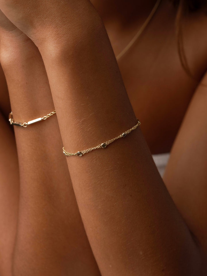 Close-up of Close By Me's Double Strand Birthstone Bracelet in 14k yellow gold on a model's wrist.