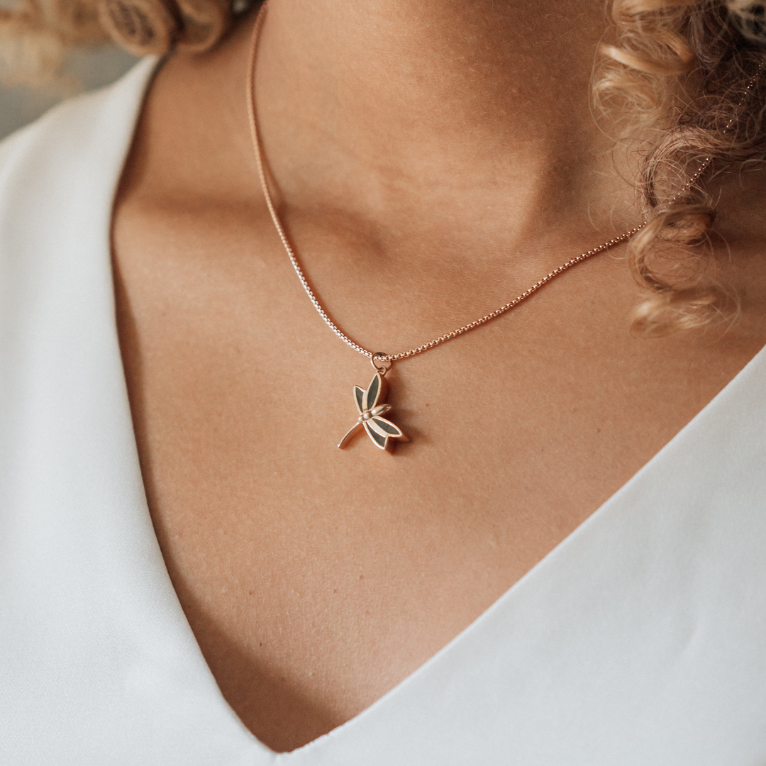 This photo shows a model wearing close by me jewelry's 14K Rose Gold Dragonfly Pendant with ashes