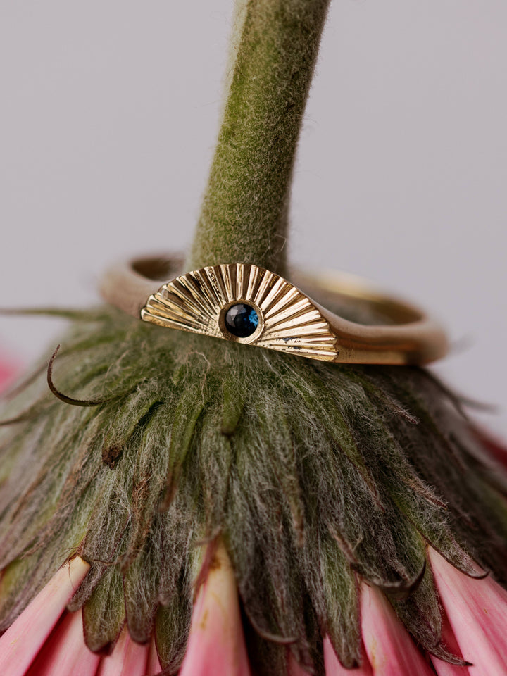 The Radiance Ring by Close By Me in 14k yellow gold on the stem of an upside down flower.