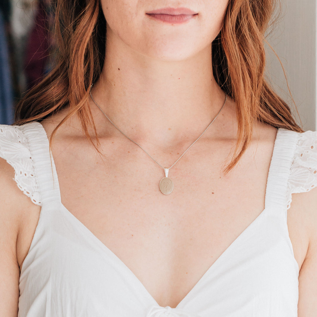 A model wearing the fancy bail oval cremation necklace in sterling silver by close by me jewelry