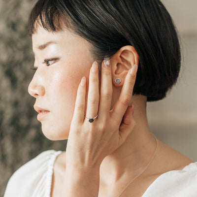 sterling silver hexagon stud earrings with ashes being worn by a model further away
