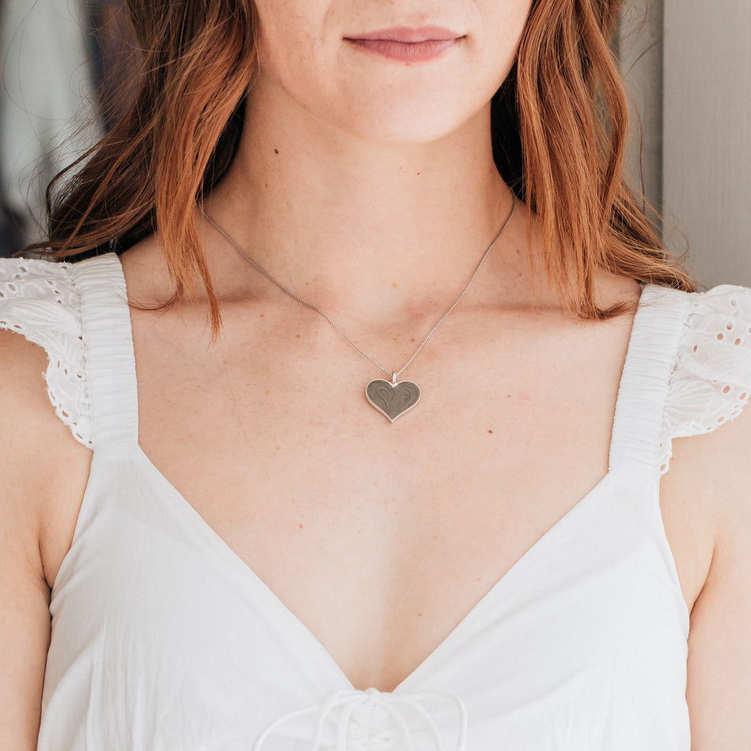 The large heart memorial necklace in sterling silver around a model's neck