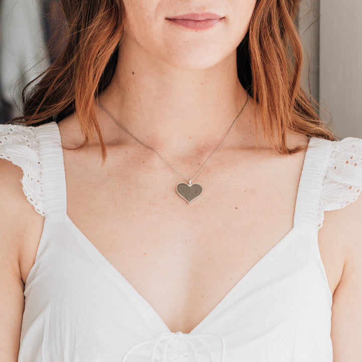 The large heart memorial necklace in sterling silver around a model's neck