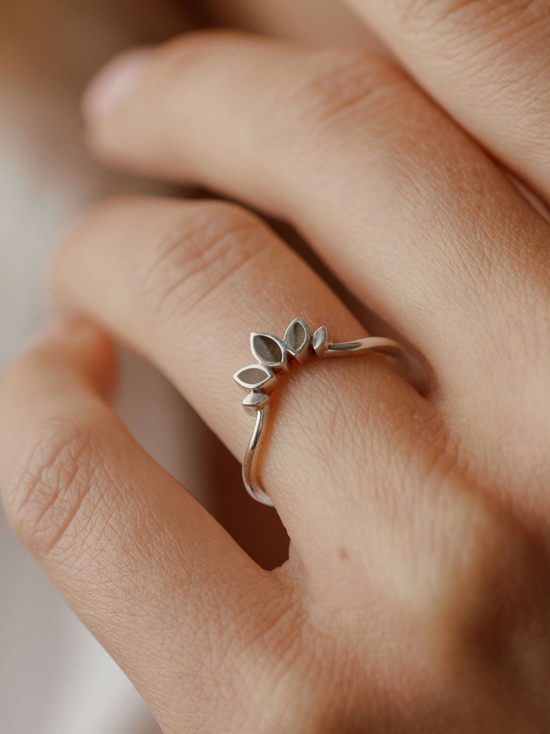 Close-up view of Close By Me's Lotus Cremation Ring in Sterling Silver on a female model's ring finger.