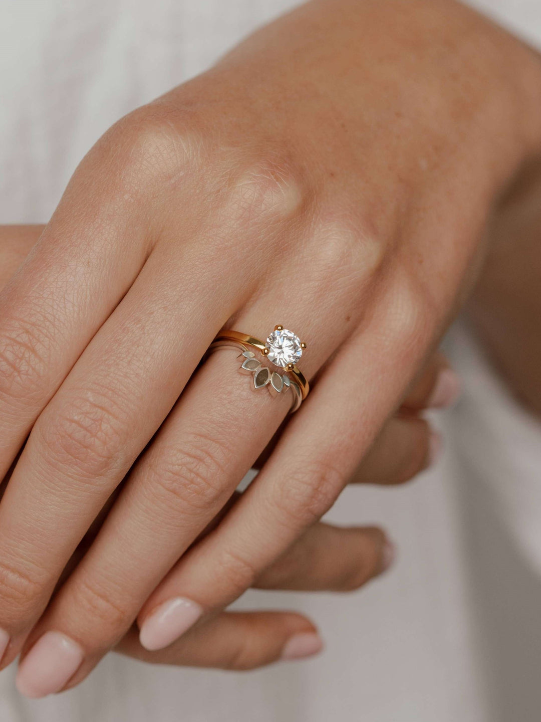 Close By Me's Lotus Cremation Ring in Sterling Silver being worn on a female model's ring finger next to a 14k yellow gold diamond engagement ring.