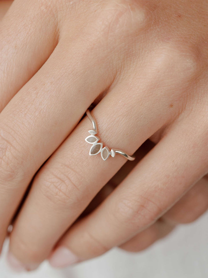 Close-up view looking down on Close By Me's Lotus Cremation Ring in Sterling Silver on the ring finger of a female model's hand.