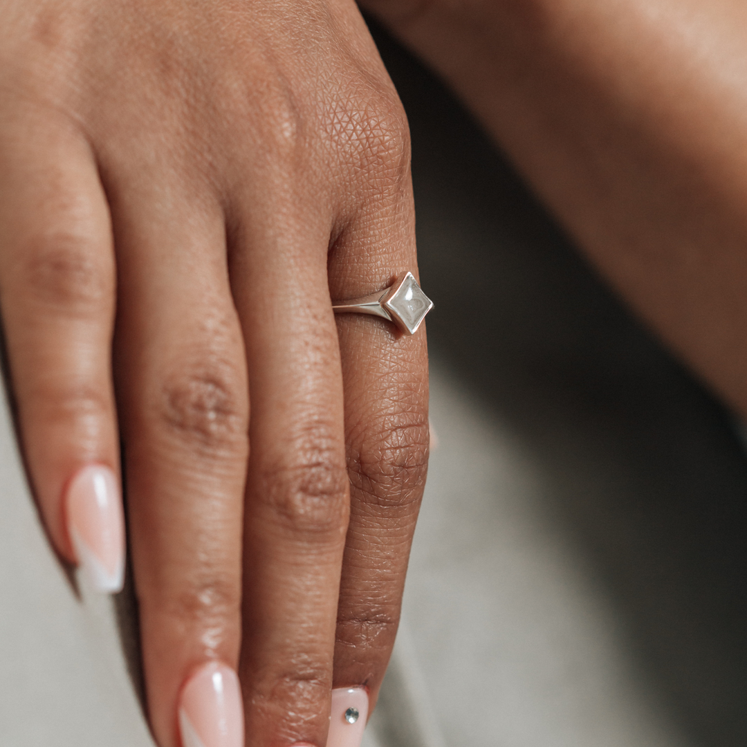 A close-up photo of a model's hand, wearing Close By Me's Sterling Silver Luminary Cremation Ring.