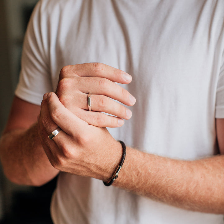 Several sterling silver mens memorial rings being worn by a male model in a white t shirt