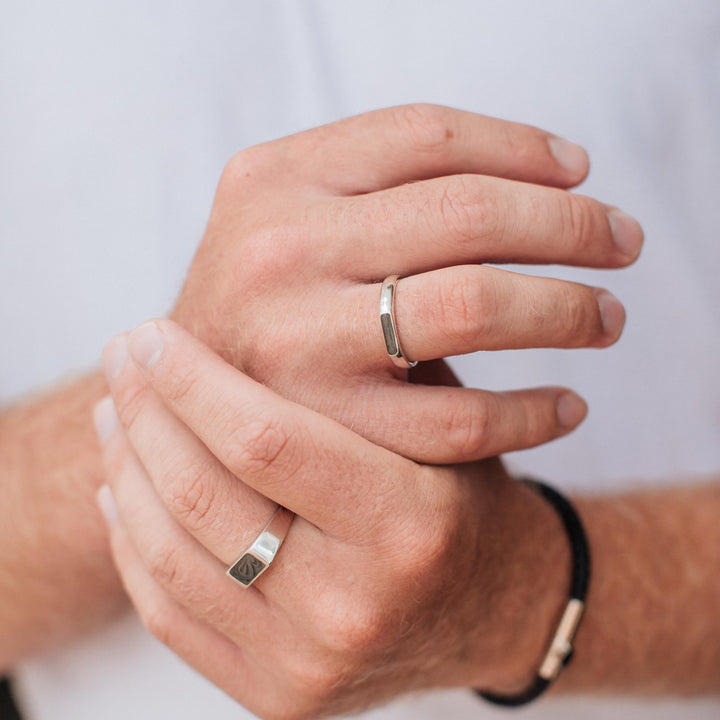A close up showing the detail of close by me jewelry's men's memorial ring designs in sterling silver being worn by a male model