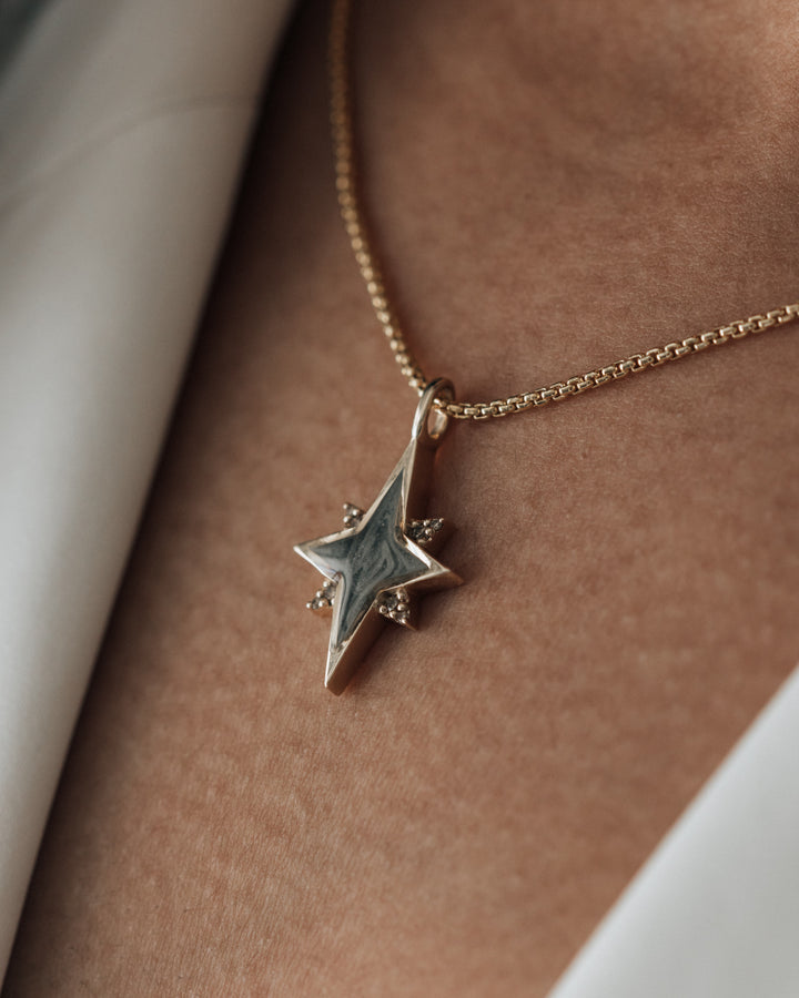 The north star pendant in 14k yellow gold with champagne diamonds being worn by a model with dark skin