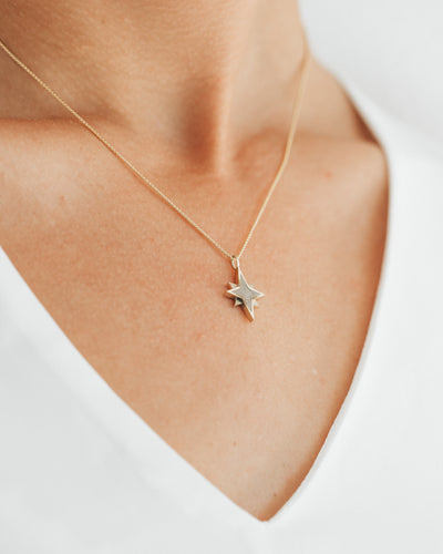 A model in a white top wearing the Sterling Silver North Star Necklace with ashes by close by me jewelry