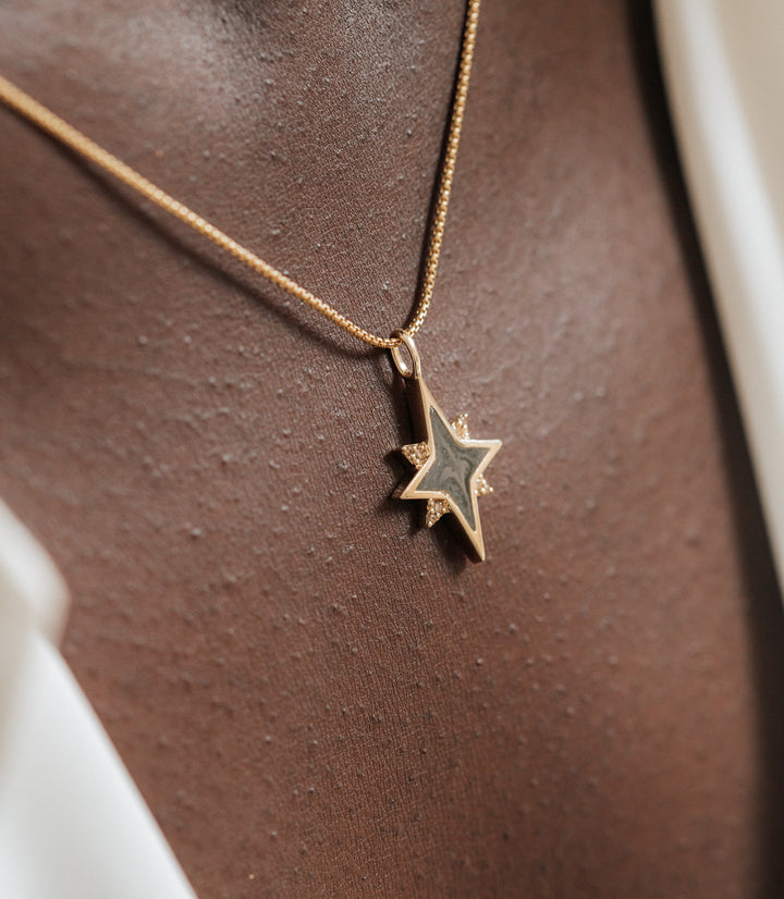 A detailed shot of the North Star Cremation Pendant with Champagne Diamonds in 14K Yellow Gold by close by me jewelry on a model with dark skin