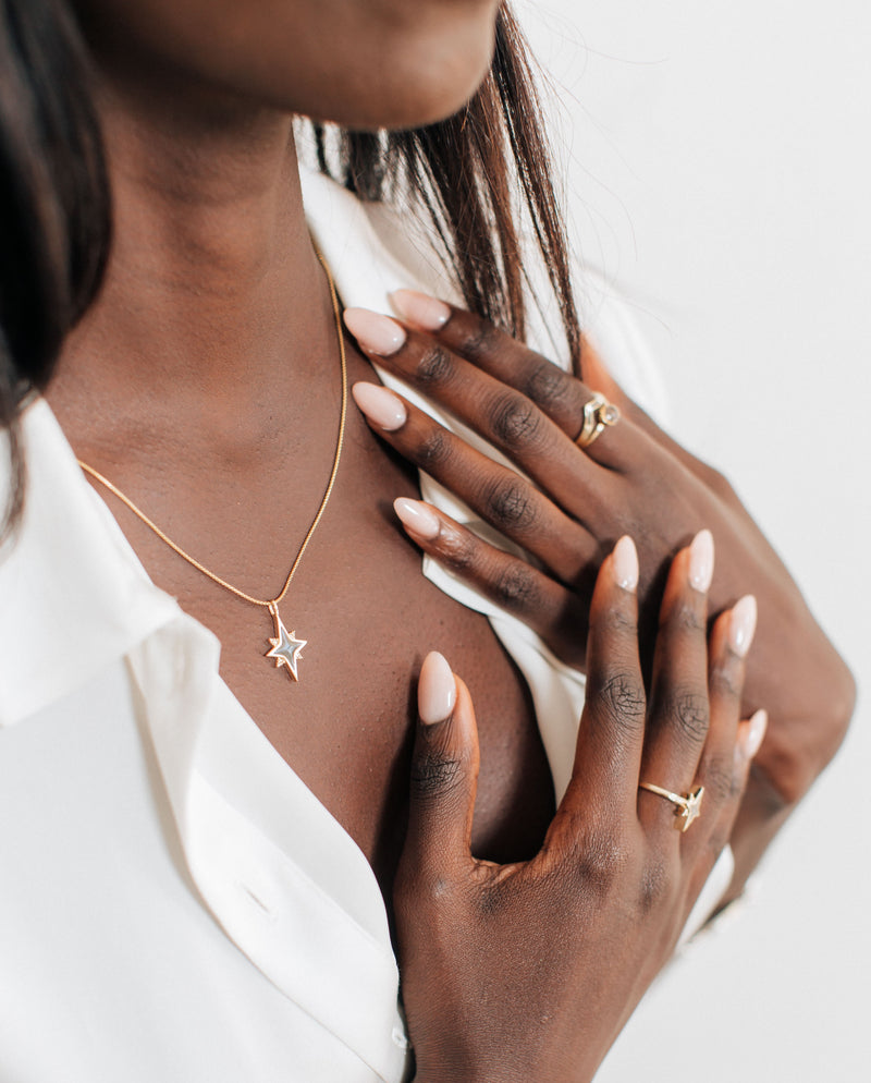 A dark skinned model in a white blouse wearing the North Star Ashes and Champagne Diamond Necklace in 14K Yellow Gold by close by me jewelry