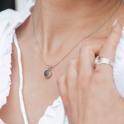 This photo shows the Sterling Silver Rabbit Ear Cremated Remains Necklace designed by close by me jewelry being worn by a light skinned model in a white top