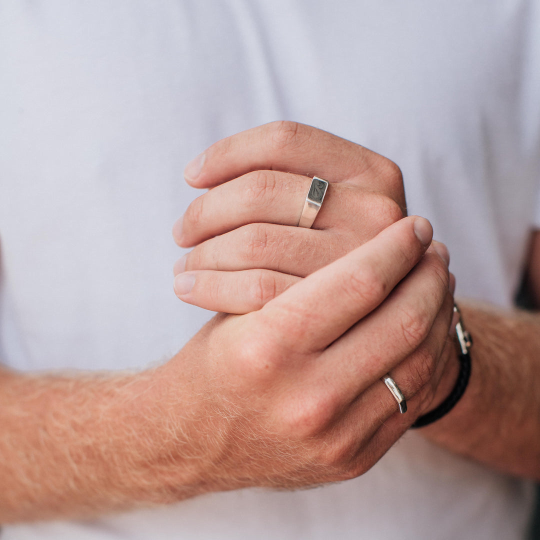 This photo shows a male model wearing the Sterling Silver Men's Rectangle Signet and Smooth Band Ring designs by close by me jewelry