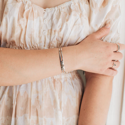 sterling silver three setting cremation cuff bracelet shown on a model wearing a floral dress