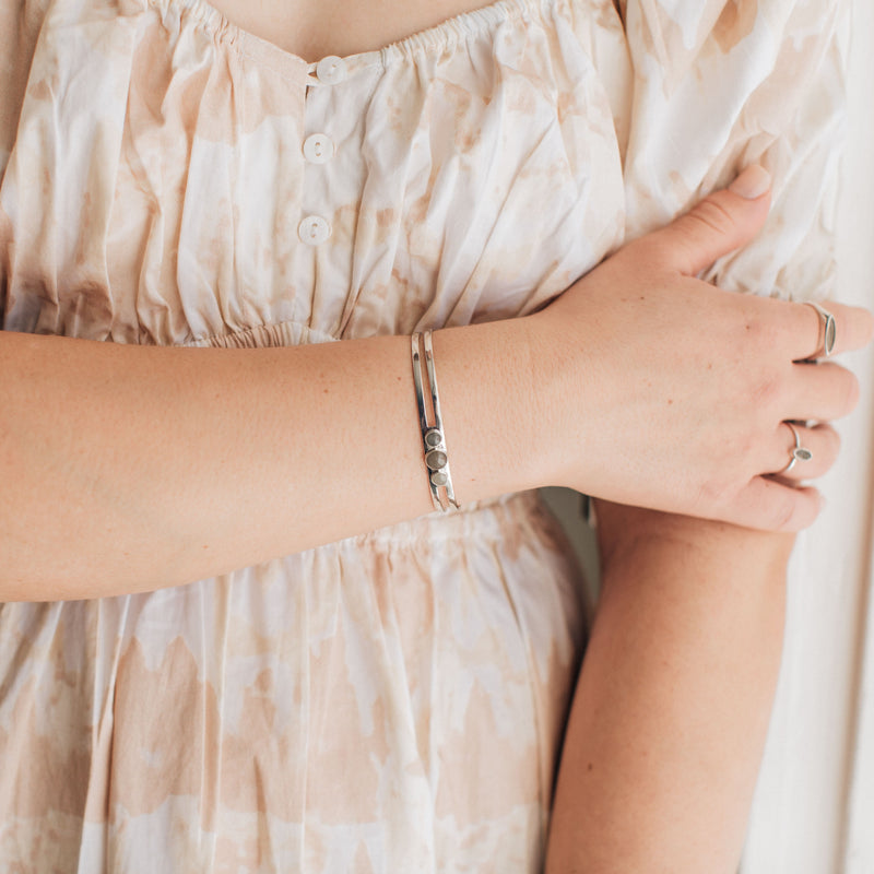 sterling silver three setting cremation cuff bracelet shown on a model wearing a floral dress
