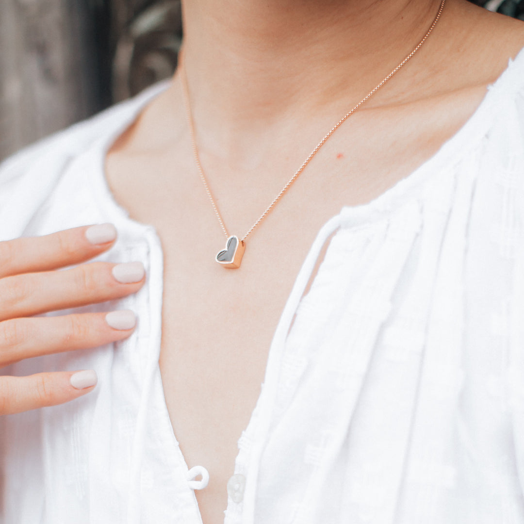 A model wearing the 14K Rose Gold Signature Heart Sliding Cremation Pendant by close by me jewelry