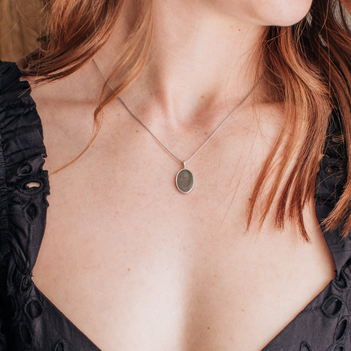A model in a black dress wearing close by me jewelry's sterling silver simple bail oval memorial necklace
