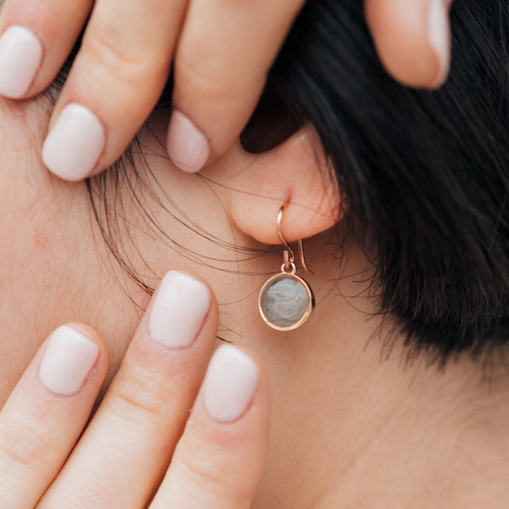 simple dome cremation earrings in 14k rose gold shown closely on a model's ear