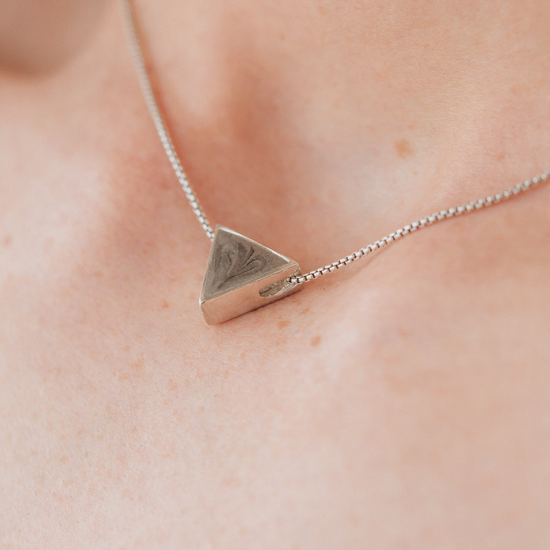 A close up showing the Triangle Sliding Cremation Pendant in Sterling Silver by close by me jewelry being worn by a model