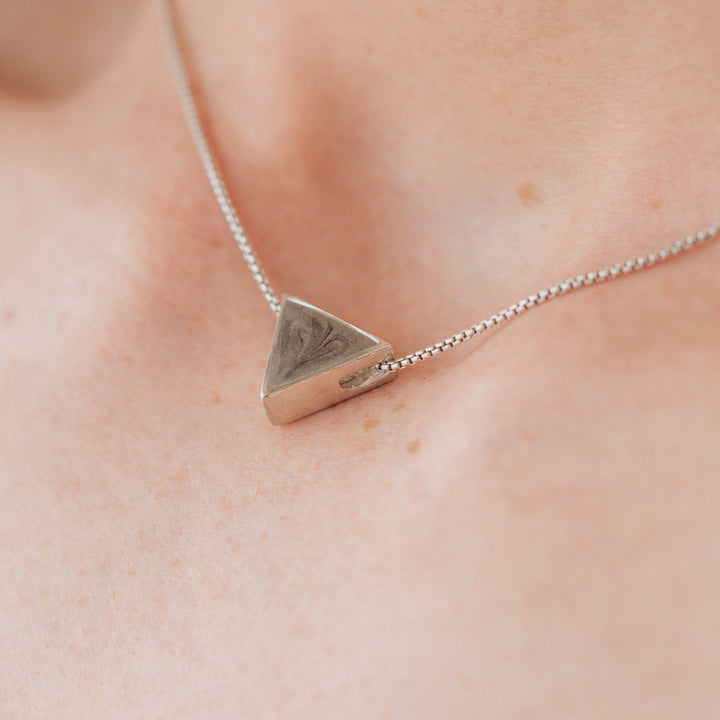 A close up showing the Triangle Sliding Cremation Pendant in Sterling Silver by close by me jewelry being worn by a model