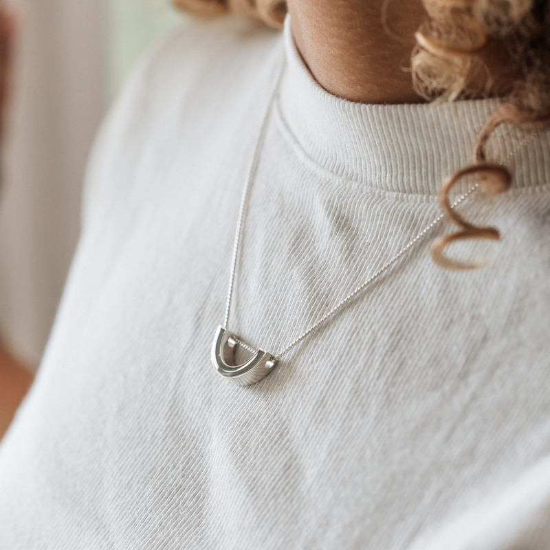 A close up showing the sliding "u" pendant with ashes designed in sterling silver by close by me jewelry around a model&