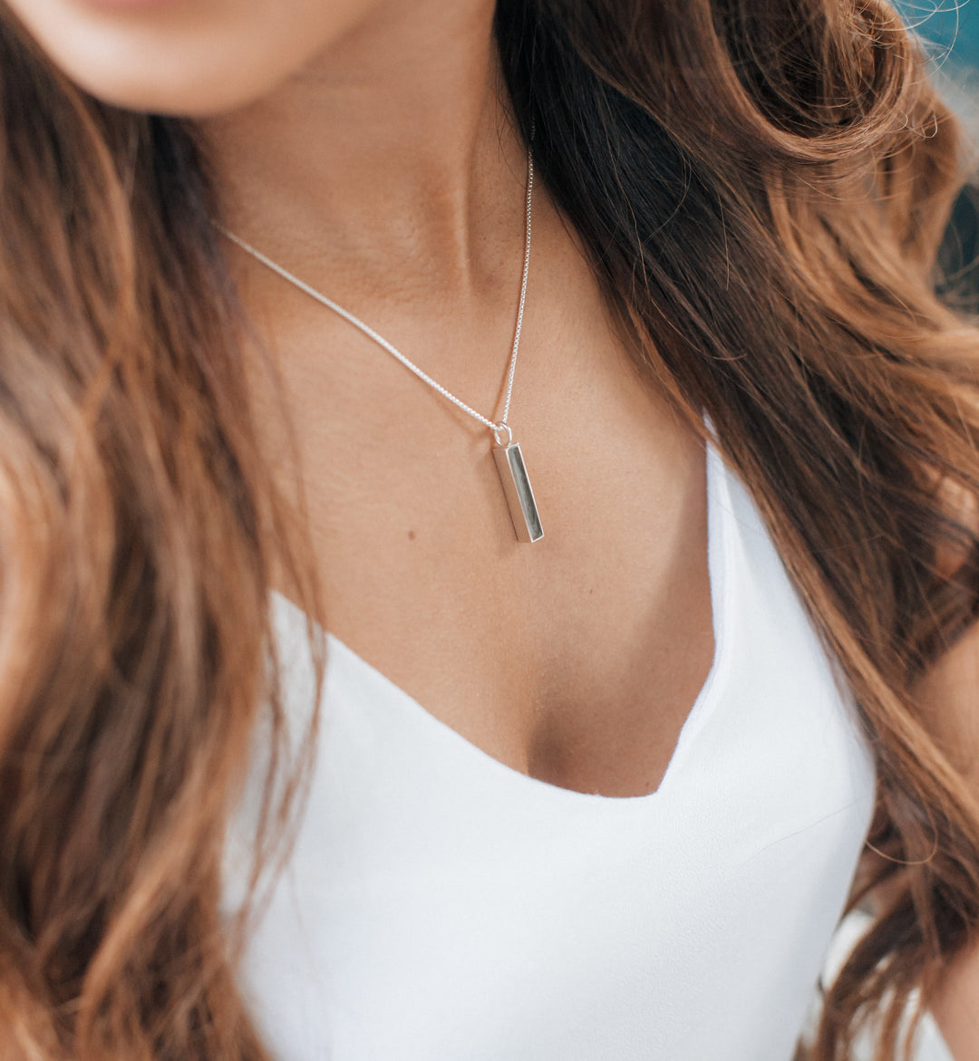 A model wearing the sterling silver small bar memorial pendant by close by me jewelry from an angle
