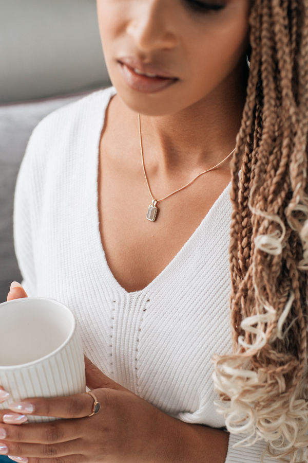 A dark-skinned model with blonde braids  in a white sweater wearing close by me jewelry's 14K Yellow Gold Small Cable Ashes Necklace