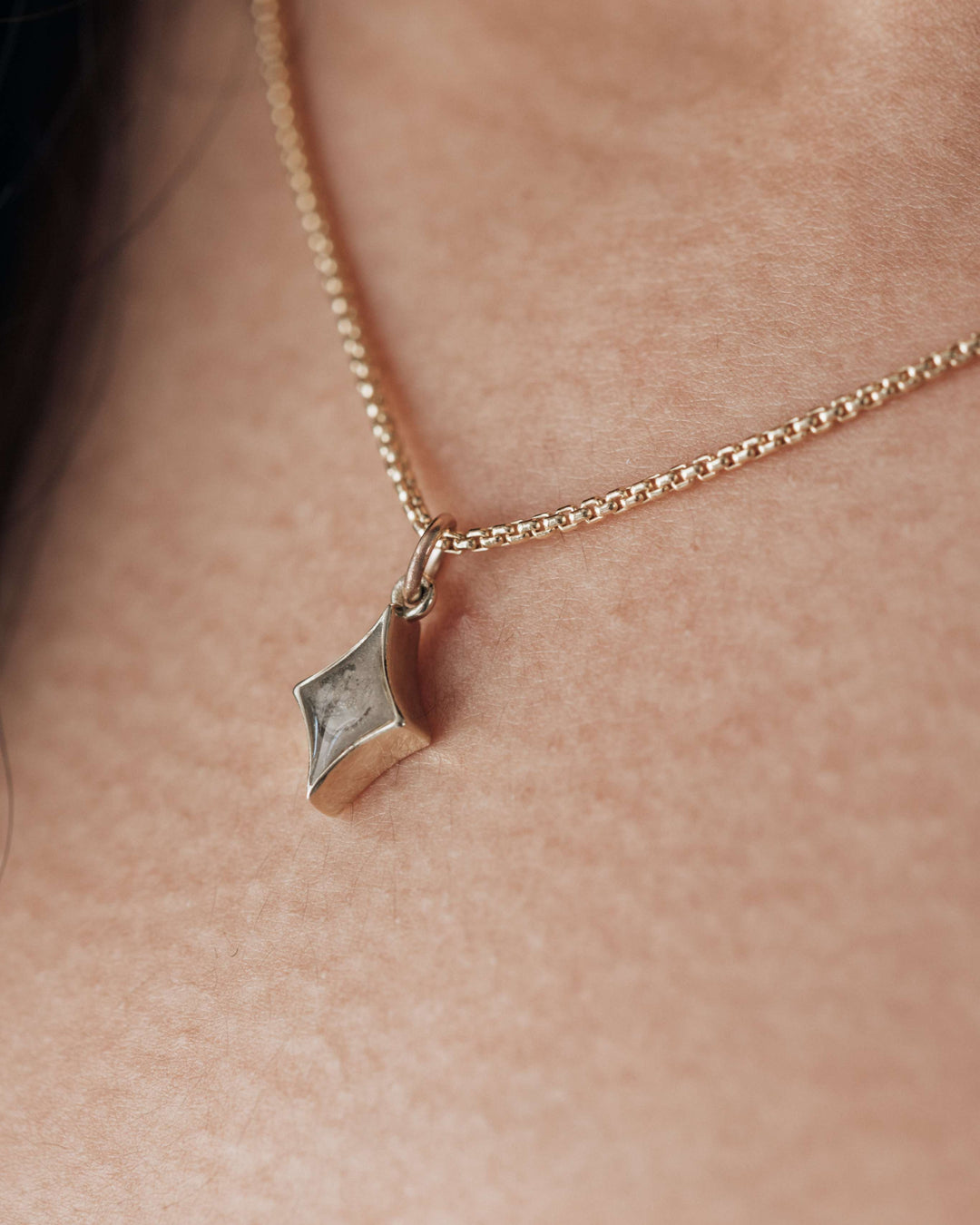 An angled and very close photo showing close by me jewelry's small diamond cremation necklace with ashes