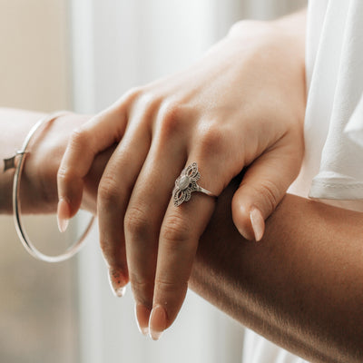 A close-up of a female model's right hand resting on her left forearm; on her finger is Close By Me's Small Setting World War II Cremation Ring.
