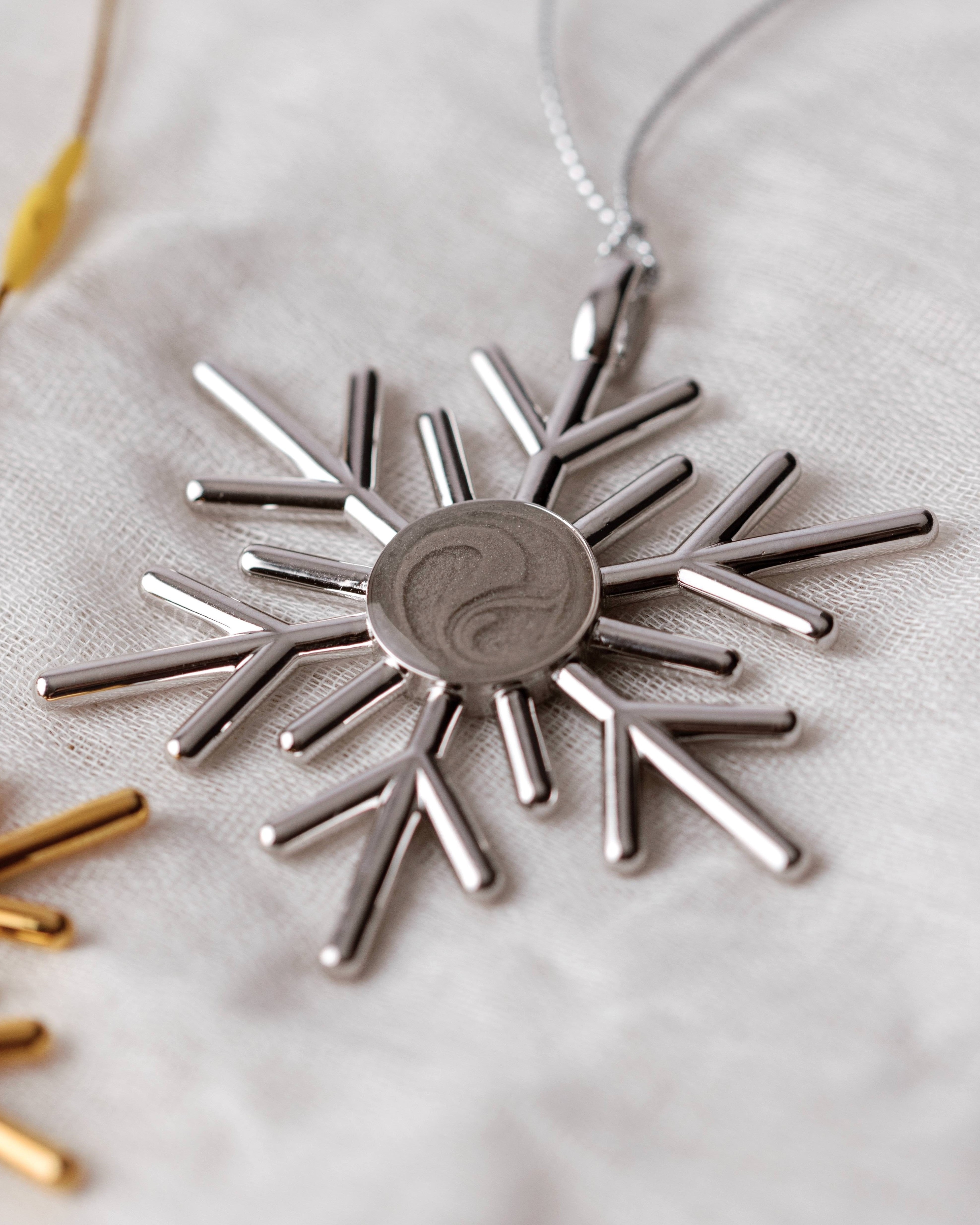 Close By Me's 2025 Snowflake Cremation Ornament in silver on a light fabric background.