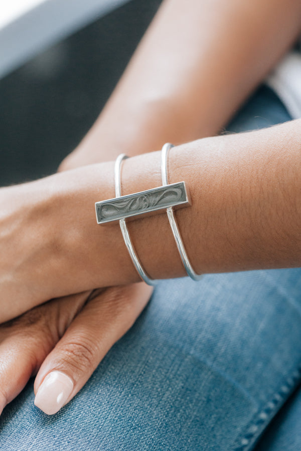 Detailed photo of a model wearing the Bar Bracelet in Sterling Silver, her wrist crossing over her other arm.