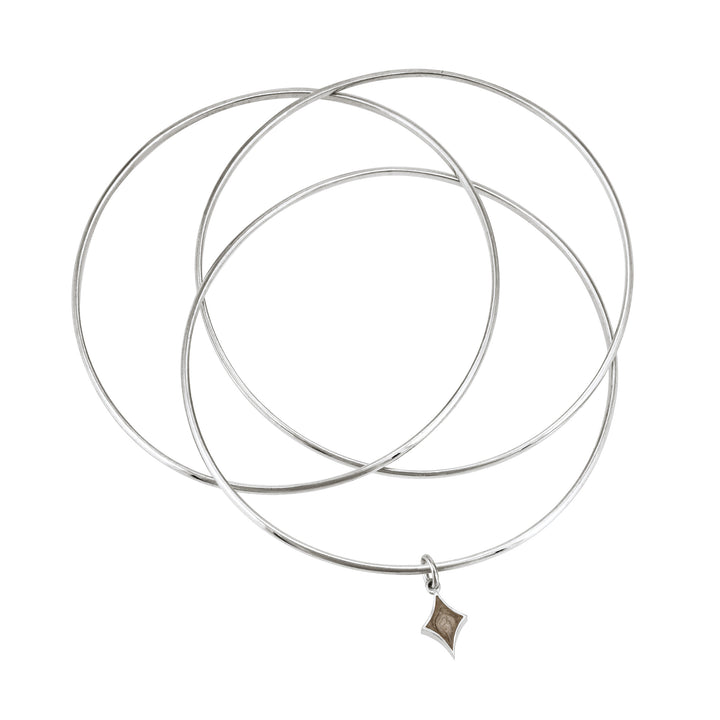 Sterling silver interlocking bangle cremation bracelet with a diamond ashes charm, shown from the top