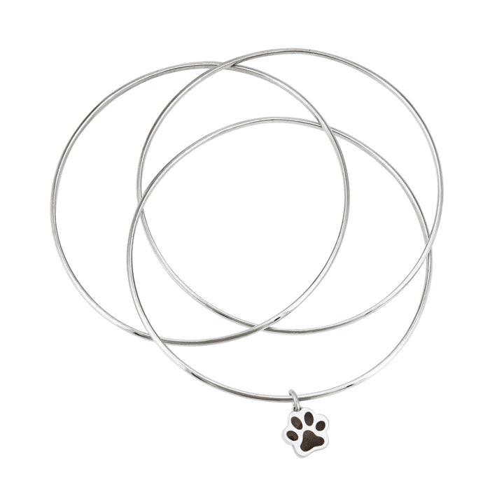 Sterling silver interlocking bangle cremation bracelet with a paw print ashes charm, shown from the top