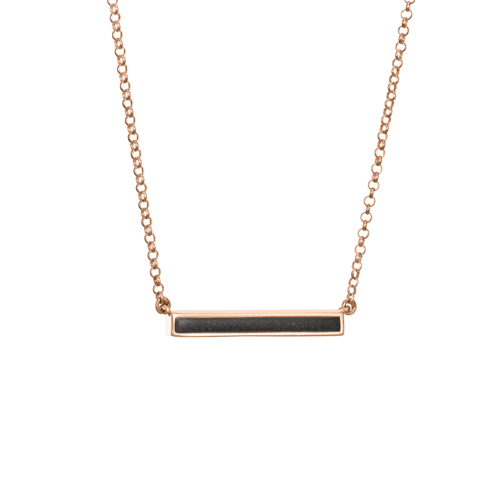 A slightly angled photo showing close by me's ashes necklace in a thin lateral bar design with an attached chain in 14k rose gold