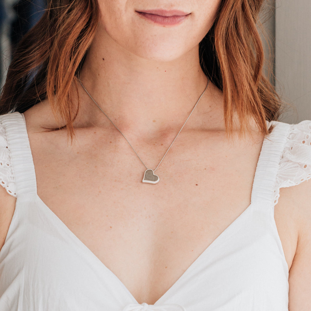 The Sterling Silver Tilted Heart Ashes Necklace by close by me around a redheaded model's neck