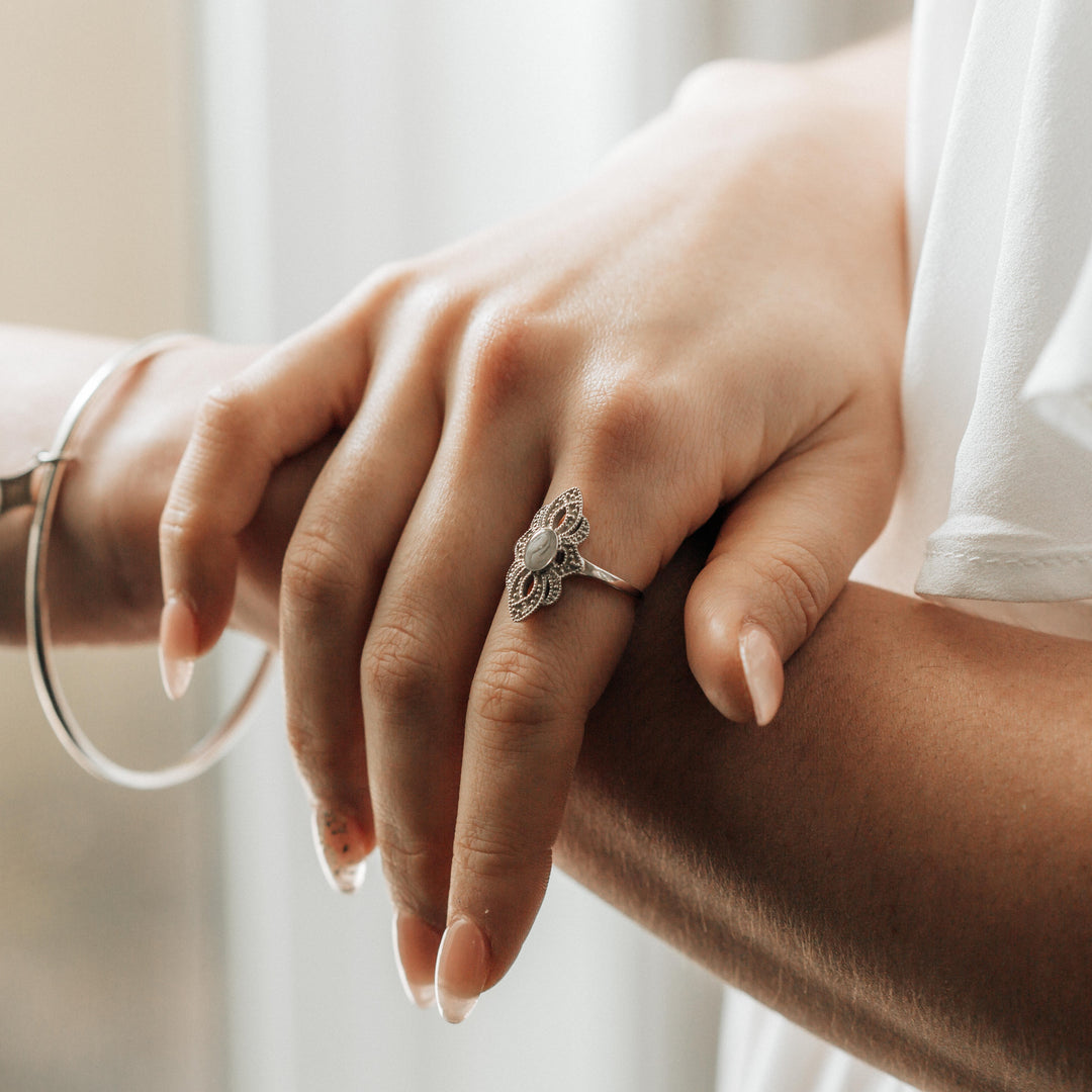 Close-up of the WWII Small Setting Cremation Ring on a woman's right index finger as she rests her hand on her left forearm.