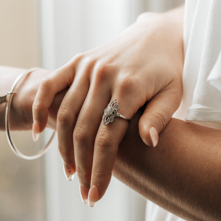 Close-up of the WWII Small Setting Cremation Ring on a woman's right index finger as she rests her hand on her left forearm.