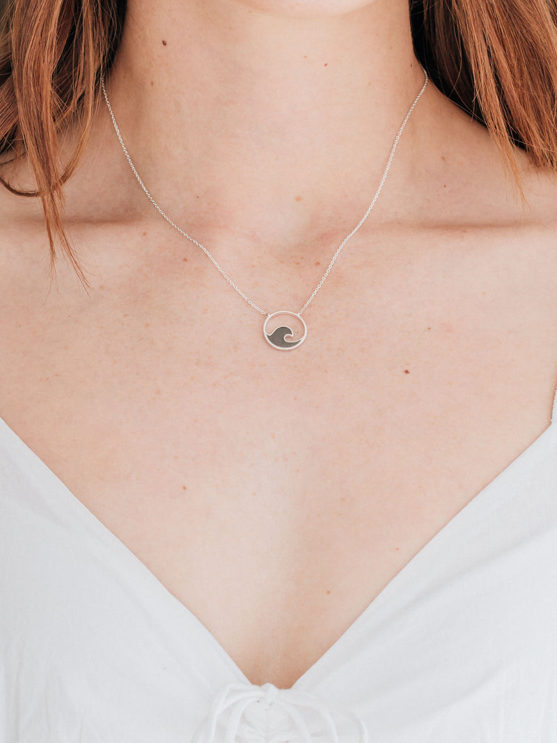 A close up showing the sterling silver wave ashes necklace designed by close by me jewelry around a model&