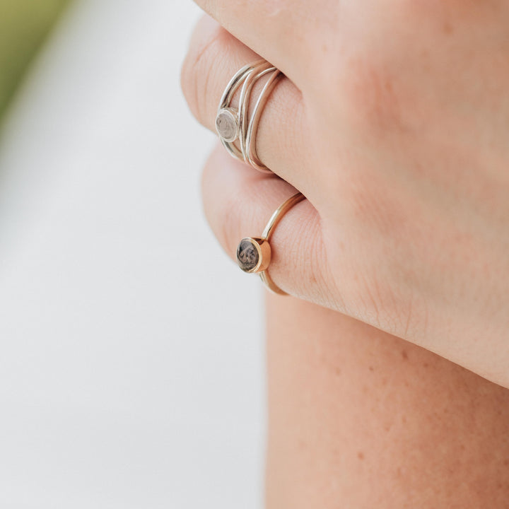 This close up photo shows the 14K Rose Gold 5mm Circle Stacking Ashes Ring by close by me jewelry on a model's photo next to another sterling silver cremation ring