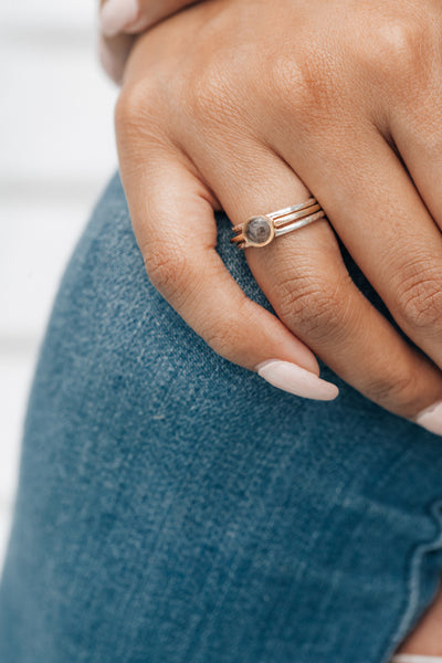Pictured here is a stacking ashes ring set by close by me jewelry on a model's ring finger. She wears the 14K Rose Gold 5mm Circle Stacking Ring with two Sterling Silver Companion Rings to complete the set.