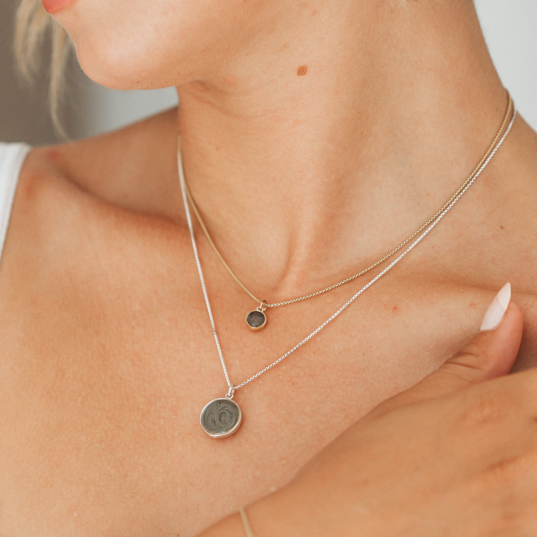 This photo shows a model wearing two sizes of close by me jewelry's dome pendant series around her neck; the pendant on the shorter chain is the 14K Yellow Gold 6mm Dome Cremains Necklace