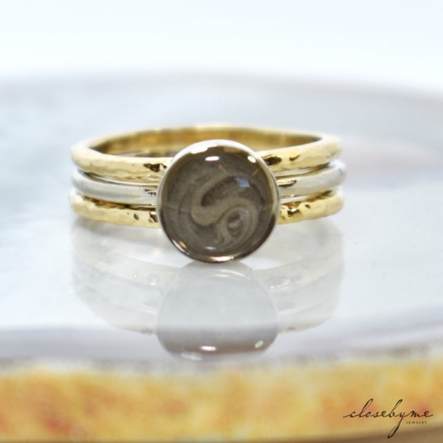 Pictured here is the 8mm Circle Stacking Cremated Remains Ring in 14K White Gold between two 14K Yellow Gold Textured Companion Rings, all designed by close by me jewelry