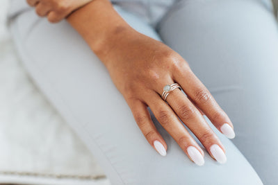 This photo shows a model wearing close by me jewelry's mixed metal stacking set on her middle finger. In the center between two Sterling Silver Smooth Companion Stacking Bands is the 14K Rose Gold 8mm Circle Stacking Ashes Ring