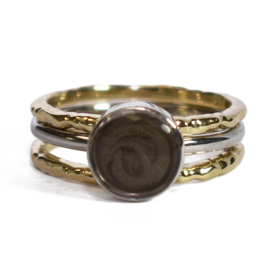 This photo shows a stacking cremation ring set from close by me jewelry from the front. The Cremains Ring is an 8mm Circle Stacking Ring in Sterling Silver between two 14K Yellow Gold Textured Companion Rings