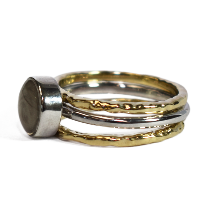 This photo shows a stacking cremation ring set from close by me jewelry from the side. The Cremains Ring is an 8mm Circle Stacking Ring in Sterling Silver between two 14K Yellow Gold Textured Companion Rings