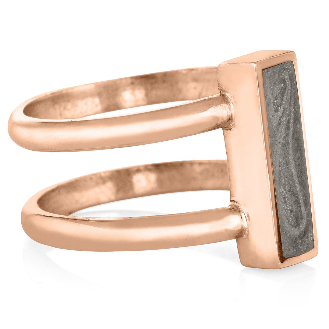 Pictured here is close by me's 14K Rose Gold Bar Cremation Ring from the side to show the thickness of its bezel and how the band attaches to the gray cremation setting