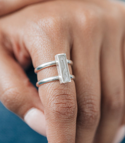 This photo shows a model wearing close by me jewelry's Sterling Silver Bar Ashes Ring on her index finger