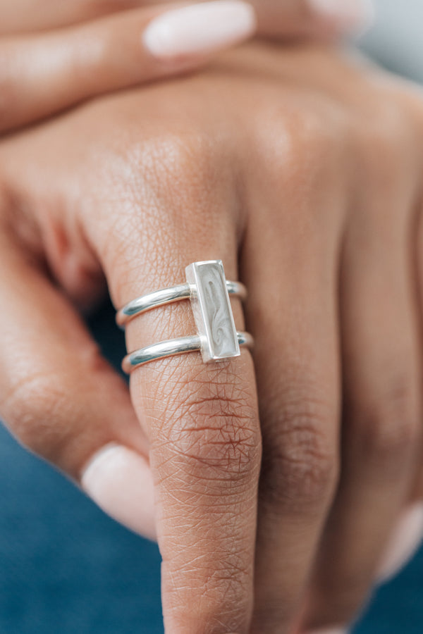 This photo shows the Sterling Silver Bar Ashes Ring on a model's index finger